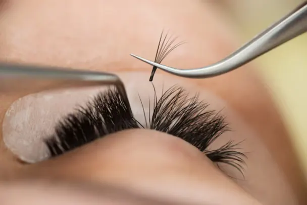 A woman receives eyelash trimming at Melody Salon, specializing in eyelash extensions.