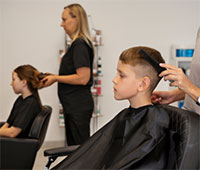 A young boy receiving a haircut at Melody Salon, surrounded by hair styling tools and a professional stylist.